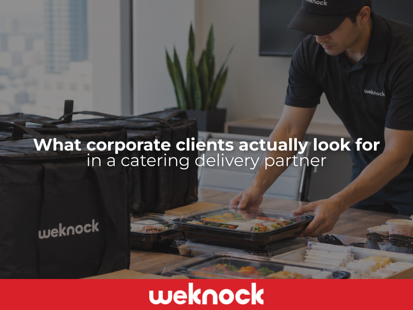 A Weknock catering delivery driver in uniform placing fresh food platters on a table, illustrating a key part of what corporate clients actually look for in a partner.