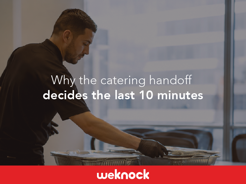 A delivery driver setting up food trays at an office buffet, executing a professional catering handoff.