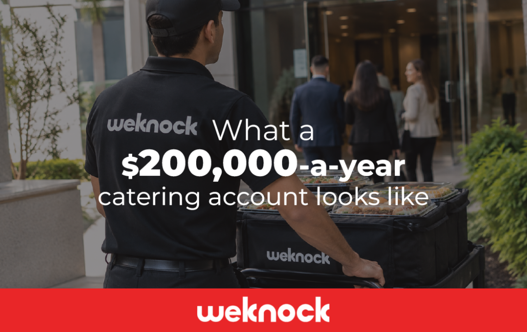 A Weknock delivery driver pushing a catering cart toward an office building to serve a high-value corporate catering account.